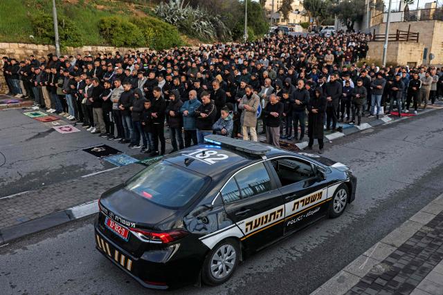 TOPSHOT - An Israeli police vehicle moves past Muslim worshippers gathering outside the Jerusalem old city walls on March 20, 2026 to attend attend the early morning prayers for Eid al-Fitr, marking the end of the holy month of Ramadan. Holy sites such as the Aqsa mosque compound in Jerusalem's old city have remained closed for security reasons since the outbreak of the Middle East war on February 28, when Israel and the US launched strikes on Iran. (Photo by AHMAD GHARABLI / AFP)