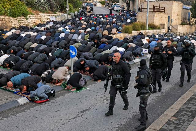 Israeli security forces walk past Muslim worshippers gathering outside the Jerusalem old city walls on March 20, 2026 to attend attend the early morning prayers for Eid al-Fitr, marking the end of the holy month of Ramadan. Holy sites such as the Aqsa mosque compound in Jerusalem's old city have remained closed for security reasons since the outbreak of the Middle East war on February 28, when Israel and the US launched strikes on Iran. (Photo by AHMAD GHARABLI / AFP)