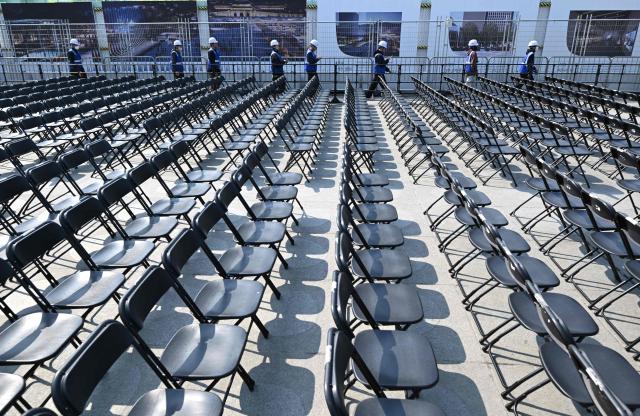 Workers walk past rows of chairs set up for the comeback concert of K-pop boy group BTS at Gwanghwamun Square in Seoul on March 20, 2026. K-pop megastars BTS released a new album on March 20, billed as reflecting the maturing boy band's Korean roots and identity, as buzz built ahead of their open-air comeback concert in the heart of Seoul. (Photo by Jung Yeon-je / AFP)