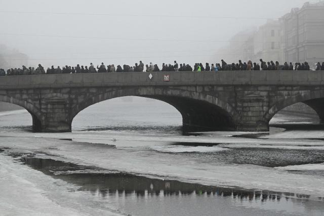 Muslim worshippers walk along a bridge over the Fontanka River after performing the early morning prayers for Eid al-Fitr, marking the end of the holy month of Ramadan, in Saint Petersburg on March 20, 2026. (Photo by Olga MALTSEVA / AFP)