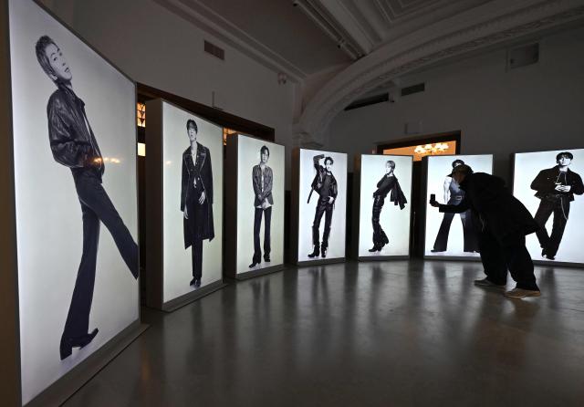 A visitor takes a picture of BTS photos displayed at a BTS pop-up store at Shinsegae Department Store's The Heritage in Seoul on March 20, 2026. K-pop megastars BTS released a new album on March 20, billed as reflecting the maturing boy band's Korean roots and identity, as buzz built ahead of their open-air comeback concert in the heart of Seoul. (Photo by Jung Yeon-je / AFP)