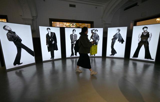 A visitor walks past BTS photos displayed at a BTS pop-up store at Shinsegae Department Store's The Heritage in Seoul on March 20, 2026. K-pop megastars BTS released a new album on March 20, billed as reflecting the maturing boy band's Korean roots and identity, as buzz built ahead of their open-air comeback concert in the heart of Seoul. (Photo by Jung Yeon-je / AFP)