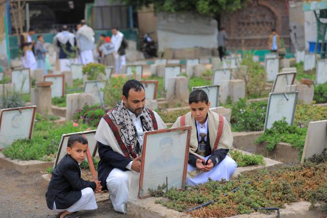 A Yemeni family visits a cemetery as they pray over the grave of their relative after the morning Eid al-Fitr prayers, which marks the end of the holy fasting month of Ramadan, in the capital Sanaa on March 20, 2026. (Photo by Mohammed HUWAIS / AFP)