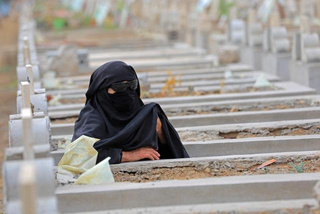 TOPSHOT - A Yemeni visits a cemetery to pray over the grave of her relative after the morning Eid al-Fitr prayers, which marks the end of the holy fasting month of Ramadan, in the capital Sanaa on March 20, 2026. (Photo by Mohammed HUWAIS / AFP)