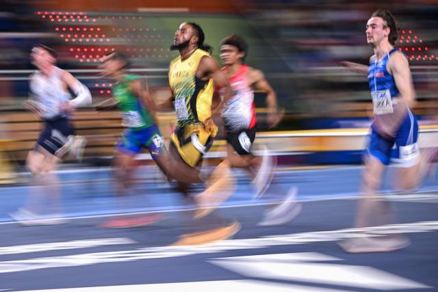 This slow shutter photograph shows Jamaica's Kishane Thompson (C) competing in the men's heats 60 metres heat 5 during the World Athletics Indoor Championships Kujawy Pomorze 2026 in Torun, Poland on March 20, 2026. (Photo by Kirill KUDRYAVTSEV / AFP)