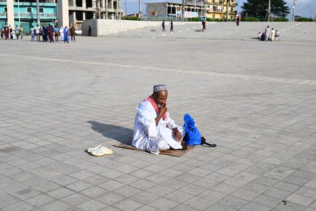 A Muslim devotee waits to offer Eid al-Fitr prayers, marking the end of the holy month of Ramadan, at the Alassane Ouattara Square in the Abobo district of Abidjan on March 20, 2026. (Photo by Sia KAMBOU / AFP)