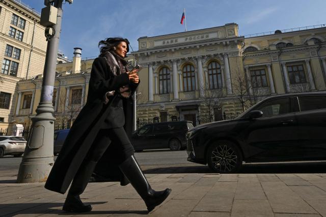 A woman walks past the Russian Central Bank headquarters in Neglinnaya street in central Moscow on March 20, 2026. Russia's central bank on March 20, 2026 cut its key interest rate to 15 percent from 15.5 percent as the economy slows under pressure from Moscow's protracted and expensive war in Ukraine and Western sanctions. (Photo by Igor IVANKO / AFP)