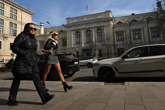 Women walk past the Russian Central Bank headquarters in Neglinnaya street in central Moscow on March 20, 2026. Russia's central bank on March 20, 2026 cut its key interest rate to 15 percent from 15.5 percent as the economy slows under pressure from Moscow's protracted and expensive war in Ukraine and Western sanctions. (Photo by Igor IVANKO / AFP)