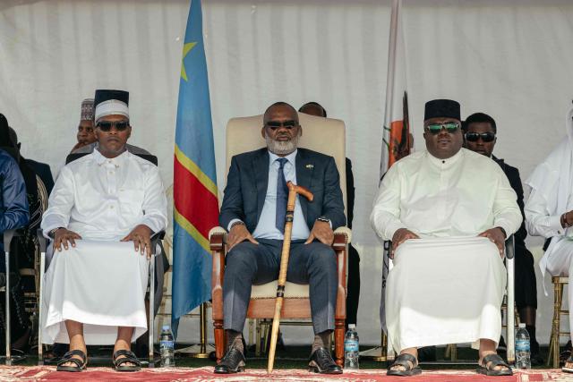Corneille Nangaa (C), coordinator of AFC/M23, and Bertrand Bisimwa (R), coordinator for political and diplomatic affairs, attends a gathering where Muslim devotees offer Eid al-Fitr prayers, marking the end of the holy month of Ramadan, at Unity Stadium in Goma on March 20, 2026. (Photo by Jospin Mwisha / AFP)