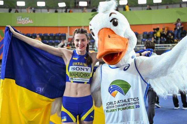 Gold medallist Ukraine's Yaroslava Mahuchikh (L) celebrates with her country's flag winning the women's final high jump event during the World Athletics Indoor Championships Kujawy Pomorze 2026 in Torun, Poland on March 20, 2026. (Photo by Kirill KUDRYAVTSEV / AFP)