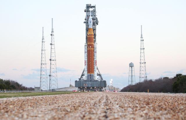 Mobile launcher 1 containing the massive Artemis II Space Launch System (SLS) rocket and Orion spacecraft rolls toward Launch Pad 39B at the Kennedy Space Center in Cape Canaveral, Florida at sunrise on March 20, 2026. NASA on March 19 began returning its towering SLS rocket and Orion spacecraft to its Florida launch pad ahead of a planned flyby of the Moon, after completing necessary repairs. Artemis engineers began the maneuver, which can take up to 12 hours, at 8:00 pm eastern, after which the US space agency will begin final preparations before its next launch window opens on April 1. (Photo by Gregg Newton / AFP)