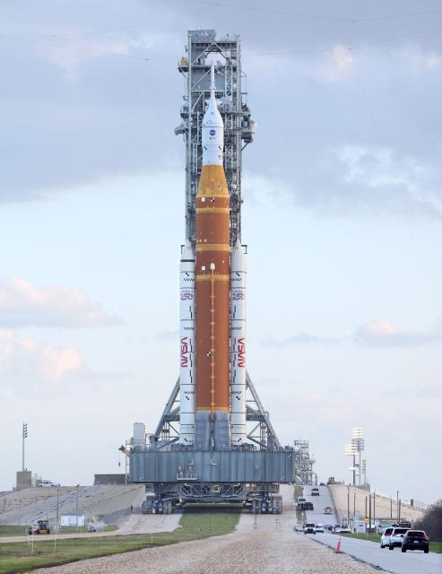 Mobile launcher 1 containing the massive Artemis II Space Launch System (SLS) rocket and Orion spacecraft rolls toward Launch Pad 39B at the Kennedy Space Center in Cape Canaveral, Florida at sunrise on March 20, 2026. NASA on March 19 began returning its towering SLS rocket and Orion spacecraft to its Florida launch pad ahead of a planned flyby of the Moon, after completing necessary repairs. Artemis engineers began the maneuver, which can take up to 12 hours, at 8:00 pm eastern, after which the US space agency will begin final preparations before its next launch window opens on April 1. (Photo by Gregg Newton / AFP)