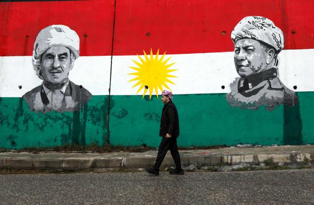 A Kurdish man walks past a mural depicting the late leader of the Kurdistan Liberation Movement Mustafa Barzan (L) and Kurdish political leader Massoud Barzani during Nowruz new year spring festival celebrations in the town of Akre, north of Erbil in Iraq's northern autonomous Kurdish region, on March 20, 2026. Millions of people across the Middle East, Asia and Eastern Europe celebrate Nowruz new year festival, which marks the start of spring. (Photo by Safin HAMID / AFP)