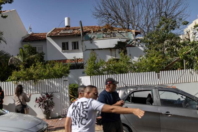 Residents look at the damage after a house was hit following a strike over Rehovot, south of Tel Aviv, on March 20, 2026. The United States and Israel began the war on February 28, 2026, by attacking Iran and killing its supreme leader. Iran retaliated with strikes against Israel and US allies and interests across the Gulf and Iraq, drawing the whole region into war (Photo by Ilia YEFIMOVICH / AFP) / 