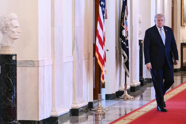 US President Donald Trump walks through the Cross Hall as he arrives for a ceremony to present the Commander-in-Chief Trophy to the Navy Midshipmen football team of the United States Naval Academy in the East Room of the White House in Washington, DC, on March 20, 2026. (Photo by Brendan SMIALOWSKI / AFP)