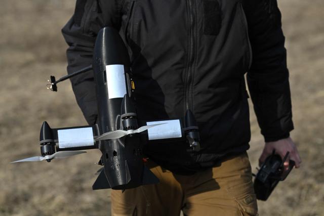 An employee of the Ukrainian SkyFall company carries a P1-Sun interceptor drone during test flights at an undisclosed location in Ukraine on March 19, 2026, amid the Russian invasion of Ukraine. (Photo by Genya SAVILOV / AFP)