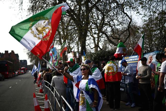 An anti-Iranian regime protesters waves an Iranian flags before the 1979 revolution with the Lion and Sun emblem at a protest, outside the Iranian Embassy in central London on March 20, 2026. (Photo by Henry NICHOLLS / AFP)
