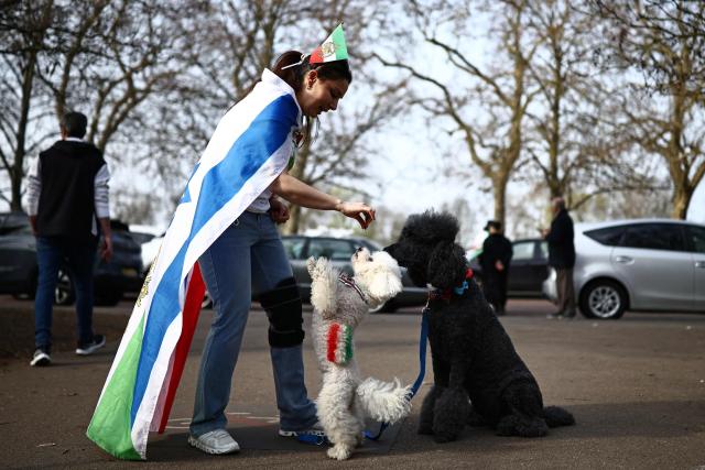 An anti-Iranian regime protester feeds dogs at a protest, outside the Iranian Embassy in central London on March 20, 2026. (Photo by Henry NICHOLLS / AFP)