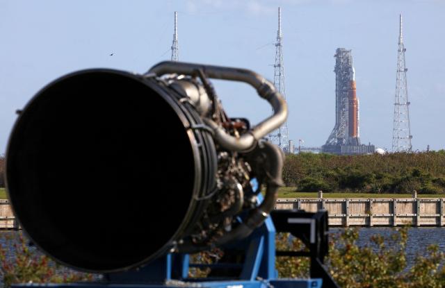 NASA's Artemis II Space Launch System (SLS) rocket and Orion spacecraft are seen at Launch Pad 39B, with one of its RS-25 engines displayed in the foreground (L), at the Kennedy Space Center in Cape Canaveral, Florida on March 20, 2026. NASA on March 19 began returning its towering SLS rocket and Orion spacecraft to its Florida launch pad ahead of a planned flyby of the Moon, after completing necessary repairs. Artemis engineers began the maneuver, which can take up to 12 hours, at 8:00 pm eastern, after which the US space agency will begin final preparations before its next launch window opens on April 1. (Photo by Gregg Newton / AFP)