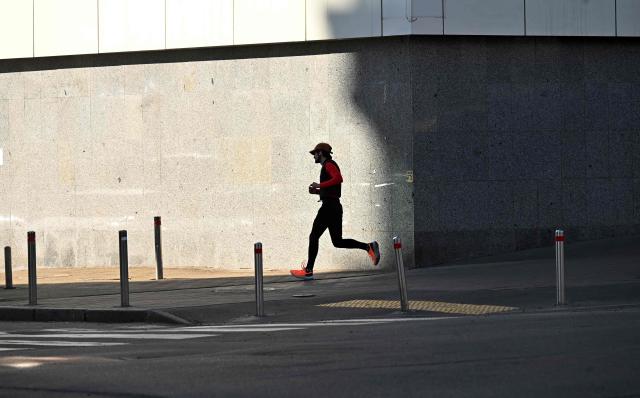 A guy jogs in downtown Kyiv during a warm spring day on March 20, 2026, amid the Russian invasion of Ukraine. (Photo by Sergei SUPINSKY / AFP)