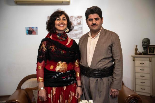 Former Kurdish fighter Saad Qazi (R) and his wife Parang Jahani pose with their traditional costumes at their apartment during the Nowruz celebrations in Erbil, the capital of Iraq's autonomous Kurdish region, on March 19, 2026. In Iraq's northern Kurdistan region, women perform a traditional dance, their long dresses spinning, gold tassels and heavy necklaces catching the firelight, as smaller crowds than usual celebrate Nowruz, overshadowed by the Middle East conflict. (Photo by Ozan KOSE / AFP)