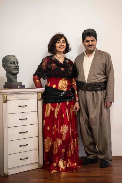 Former Kurdish fighter Saad Qazi (R) and his wife Parang Jahani pose with their traditional costumes at their apartment during the Nowruz celebrations in Erbil, the capital of Iraq's autonomous Kurdish region, on March 19, 2026. In Iraq's northern Kurdistan region, women perform a traditional dance, their long dresses spinning, gold tassels and heavy necklaces catching the firelight, as smaller crowds than usual celebrate Nowruz, overshadowed by the Middle East conflict. (Photo by Ozan KOSE / AFP)