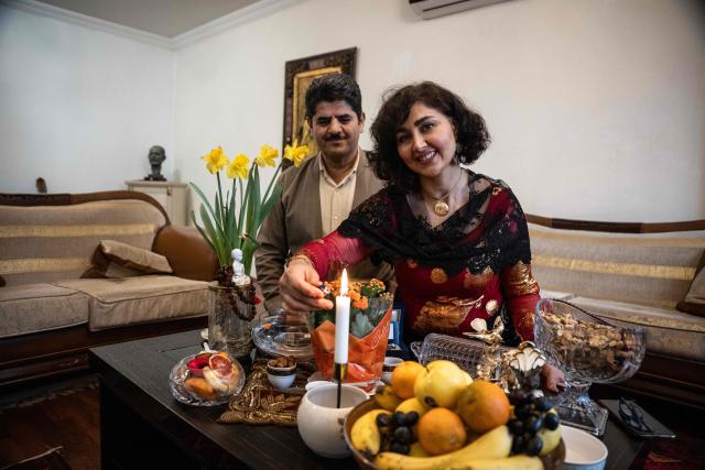 Former Kurdish fighter Saad Qazi (L) and his wife Parang Jahani pose with their traditional costumes at their apartment during the Nowruz celebrations in Erbil, the capital of Iraq's autonomous Kurdish region, on March 19, 2026. In Iraq's northern Kurdistan region, women perform a traditional dance, their long dresses spinning, gold tassels and heavy necklaces catching the firelight, as smaller crowds than usual celebrate Nowruz, overshadowed by the Middle East conflict. (Photo by Ozan KOSE / AFP)