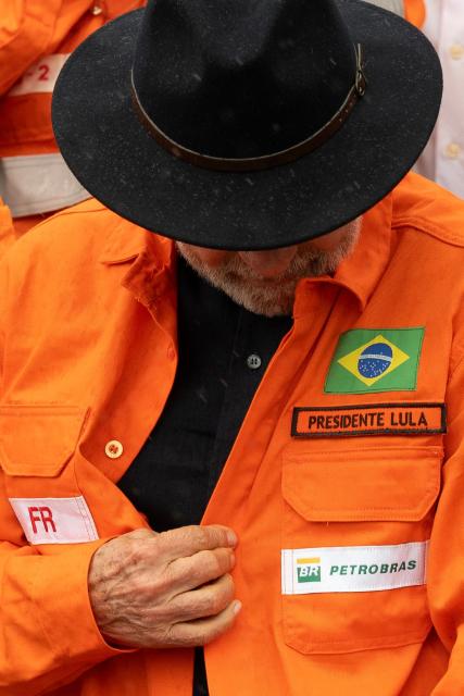 Brazil's President Luiz Inacio Lula da Silva looks at his shirt during an event to announce Petrobras' investments at the Gabriel Passos Refinery in Betim, Minas Gerais state, Brazil, on March 20, 2026. (Photo by Douglas MAGNO / AFP)