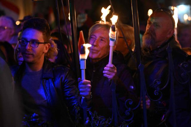 Supporters of Hungarian Prime Minister Viktor Orban hold torches as they listen to his speech at Szentendre town on March 20, 2026 as he continued his national campaign tour. Orban arrived directly from the Brussels EU summit to address supporters on key national issues in Szentendre, one of several stops on the Prime Minister’s nationwide tour ahead of the April parliamentary election. (Photo by Attila KISBENEDEK / AFP)
