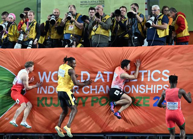 Poland's Oliwer Wdowik (L), Jamaica's Kishane Thompson, Japan's Yoshiki Kinashi and Cameroon's Claude Itoungue Bogognie arrive in the finish area next to photographers as they compete in the men's 60 metres semi-final heat 2 during the World Athletics Indoor Championships Kujawy Pomorze 2026 in Torun, Poland on March 20, 2026. (Photo by Kirill KUDRYAVTSEV / AFP)