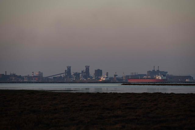 This photograph shows crude oil tanker "STI Gladiator" (R) and the blast furnaces of the ArcelorMittal steel and metallurgy site (Rear C) at the deep-water commercial and industrial port of Fos-sur-Mer, near Marseille, southern France, on March 20, 2026.  (Photo by Elodie CLEMENT / AFP)