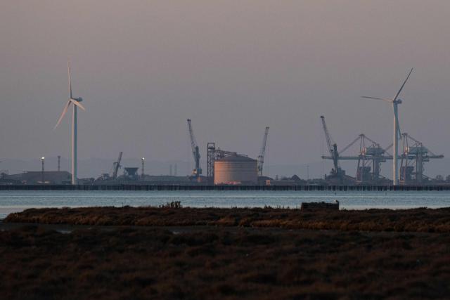 This photograph shows cranes, a storage tank of an oil refinery and wind turbines at the deep-water commercial and industrial port of Fos-sur-Mer, near Marseille, southern France, on March 20, 2026.  (Photo by Elodie CLEMENT / AFP)