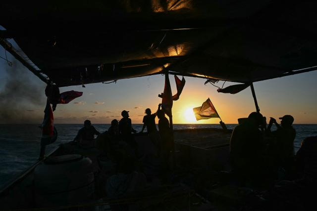 Silhouettes of activists are seen aboard the Mexican boat nicknamed ‘Grandma 2’, already in the Caribbean Sea after setting sail with 30 tons of humanitarian aid bound for Cuba, as part of the Convoy to Cuba organized by left-wing activists from several countries in the Americas and Europe, in Caribbean Sea on March 20, 2026. The first shipment of international aid for crisis-hit Cuba arrived in the country from Europe on March 18, 2026 in the shape of five tons of medical supplies. (Photo by YURI CORTEZ / AFP)