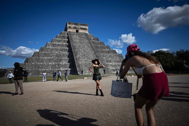 A woman poses for a photo a people gather to watch as the shape of a serpent is cast via shadows on the El Castillo pyramid in Chichen Itza on the day of the equinox, Yucatan State, Mexico, on March 20, 2026. The Chichen Itza equinox is a twice-yearly event (spring and fall) where sunlight and shadow create the illusion of a serpent, the deity Kukulcan on the world famous landmark, Chichen Itza’s main pyramid. (Photo by Carl de Souza / AFP)