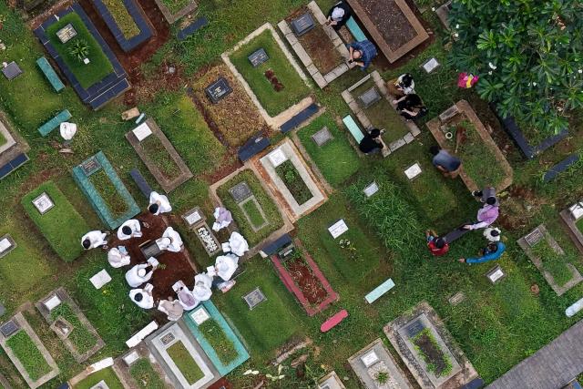 This aerial picture shows Muslim devotees visiting and cleaning graves of their families and relatives while celebrating Eid al-Fitr, marking the end of the holy month of Ramadan, in Jakarta on March 21, 2026. (Photo by BAY ISMOYO / AFP)