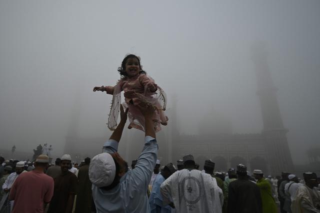 A Muslim devotee lifts a child after offering prayers, marking the end of the holy month of Ramadan, at Jama Masjid in the old quarters of new Delhi on March 21, 2026. (Photo by Arun SANKAR / AFP)