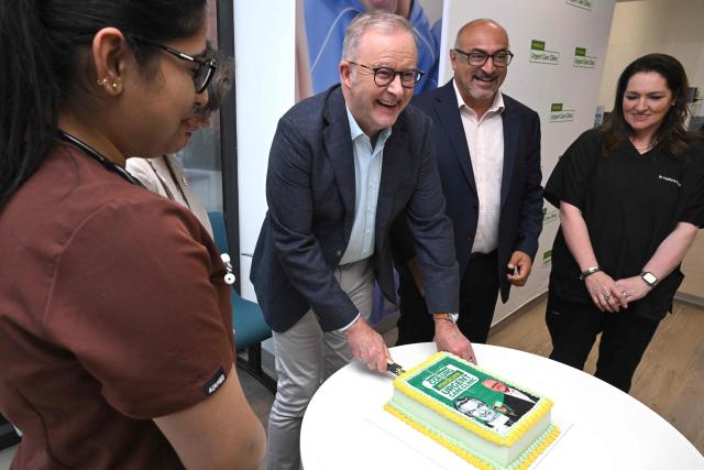 Australia's Prime Minister Anthony Albanese (C) cuts a cake during the opening of a medical centre in the Melbourne suburb of Coburg on March 21, 2026. Albanese answered questions relating to the fuel crisis and comments by US President Trump. (Photo by William WEST / AFP)