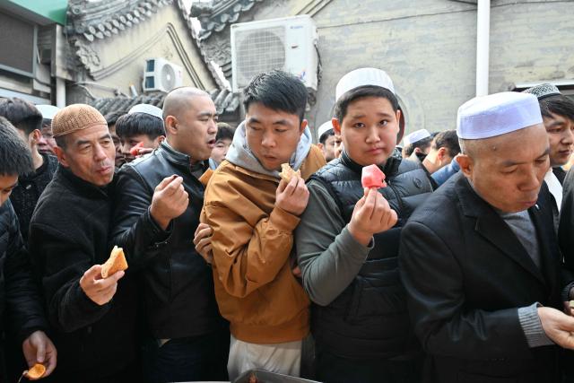 Muslim devotees eat food during Eid Al-Fitr celebrations, which marks the end of the Islamic holy fasting month of Ramadan, at a mosque in Beijing on March 21, 2026. (Photo by ADEK BERRY / AFP)