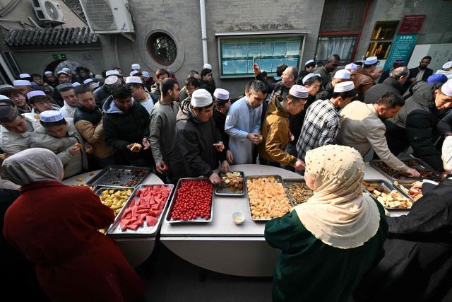 Muslim devotees eat food during Eid Al-Fitr celebrations, which marks the end of the Islamic holy fasting month of Ramadan, at a mosque in Beijing on March 21, 2026. (Photo by ADEK BERRY / AFP)
