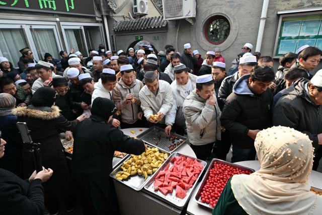 Muslim devotees eat food during Eid Al-Fitr celebrations, which marks the end of the Islamic holy fasting month of Ramadan, at a mosque in Beijing on March 21, 2026. (Photo by ADEK BERRY / AFP)