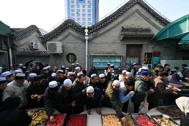 Muslim devotees eat food during Eid Al-Fitr celebrations, which marks the end of the Islamic holy fasting month of Ramadan, at a mosque in Beijing on March 21, 2026. (Photo by ADEK BERRY / AFP)
