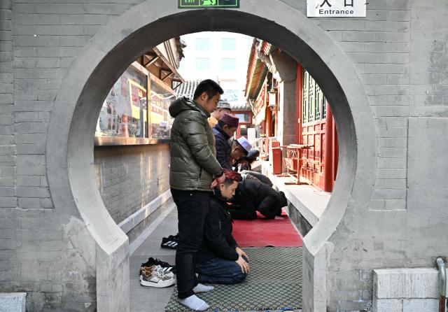 Muslim devotees offer prayers during Eid Al-Fitr, which marks the end of the Islamic holy fasting month of Ramadan, at a mosque in Beijing on March 21, 2026. (Photo by ADEK BERRY / AFP)