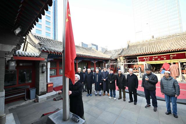 Muslim devotees conduct a national flag ceremony prior to Eid Al-Fitr prayers, which marks the end of the Islamic holy fasting month of Ramadan, at a mosque in Beijing on March 21, 2026. (Photo by ADEK BERRY / AFP)