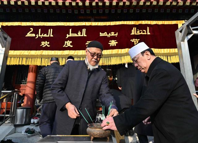 Muslim devotees place incense sticks prior to Eid Al-Fitr prayers, which marks the end of the Islamic holy fasting month of Ramadan, at a mosque in Beijing on March 21, 2026. (Photo by ADEK BERRY / AFP)