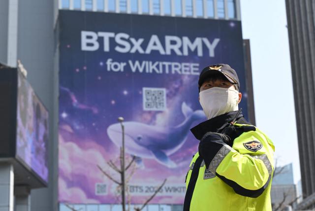 A police officer stands guard as BTS fans arrive at the venue of the comeback concert of K-pop boy group BTS in downtown Seoul on March 21, 2026. The world's biggest boy band BTS reunites on March 21, for an open-air comeback concert in the heart of Seoul, expected to draw around 250,000 people and beamed live across the globe. (Photo by Jung Yeon-je / AFP)
