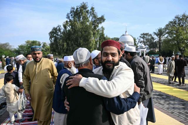 Muslim devotees hug each other after offering Eid al-Fitr prayers, which marks the end of the Islamic holy fasting month of Ramadan, in Rawalpindi on March 21, 2026. (Photo by Farooq NAEEM / AFP)