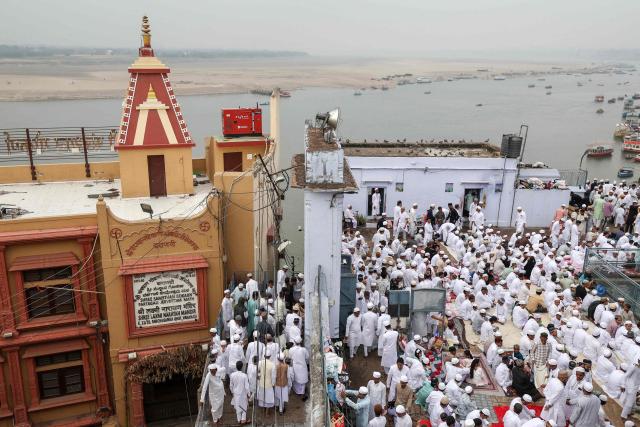 Muslim devotees arrive to offer Eid al-Fitr prayers, which marks the end of the Islamic holy fasting month of Ramadan, at Alamgir Mosque (R) along the banks of the river Ganges in Varanasi on March 21, 2026. (Photo by Niharika KULKARNI / AFP)