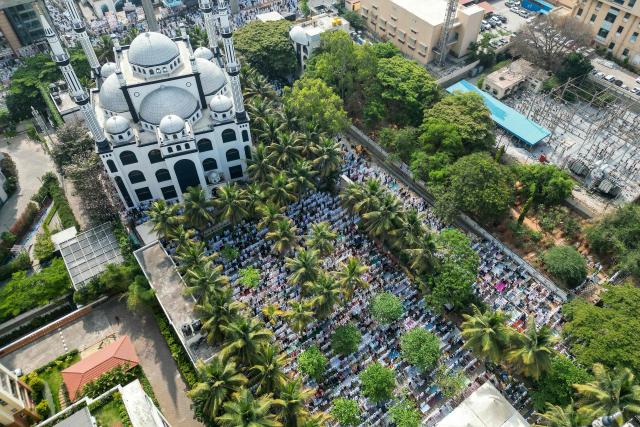 An aerial view shows Muslim devotees offering Eid al-Fitr prayers, which marks the end of the Islamic holy fasting month of Ramadan, at the Masjid-e-Bilal in Bengaluru on March 21, 2026. (Photo by Idrees MOHAMMED / AFP)