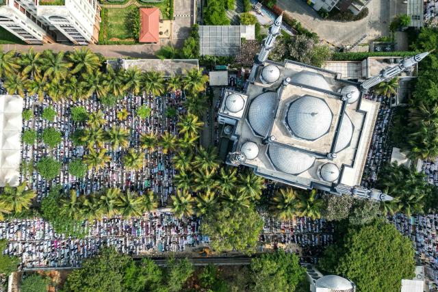 An aerial view shows Muslim devotees offering Eid al-Fitr prayers, which marks the end of the Islamic holy fasting month of Ramadan, at the Masjid-e-Bilal in Bengaluru on March 21, 2026. (Photo by Idrees MOHAMMED / AFP)