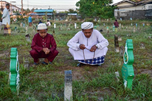 Thai Muslims pray before the grave of their relative during Eid al-Fitr, which marks the end of the holy fasting month of Ramadan, at Ban Yakang Cemetery in the southern Thai province of Narathiwat on March 21, 2026. (Photo by Madaree TOHLALA / AFP)